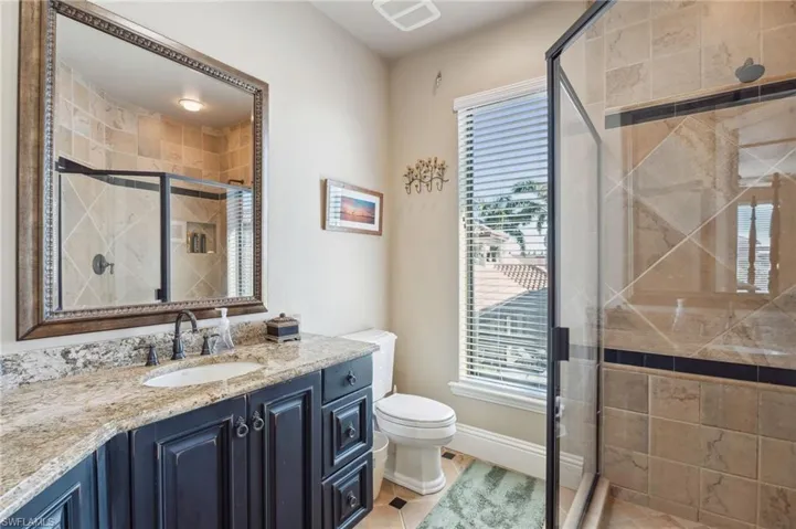Bathroom with tile patterned floors, a shower with shower door, vanity, and toilet