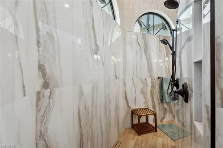 Bathroom with a tile shower, tile walls, and hardwood / wood-style flooring