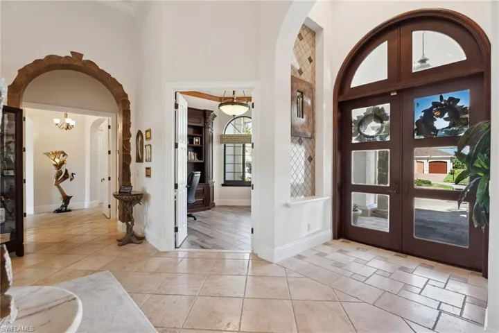 Foyer entrance with light wood-type flooring, a high ceiling, a chandelier, and french doors
