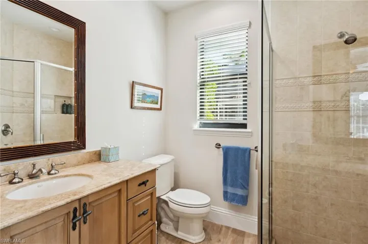 Bathroom with an enclosed shower, hardwood / wood-style flooring, vanity, and toilet