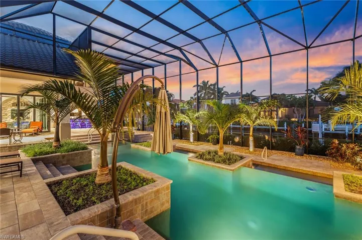 Pool at dusk with a lanai and a patio area