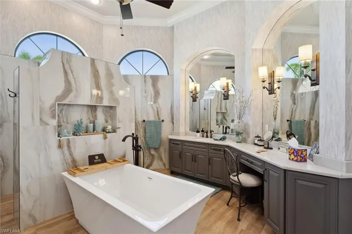 Bathroom featuring wood-type flooring, ceiling fan, and a healthy amount of sunlight
