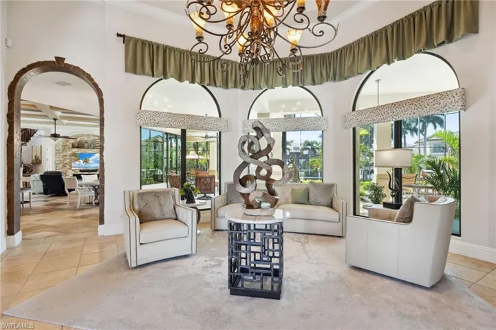 Living room with ceiling fan with notable chandelier, a towering ceiling, and tile patterned floors