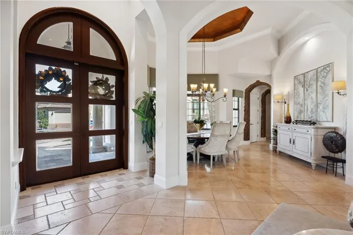 Entryway with a towering ceiling, french doors, crown molding, and a chandelier