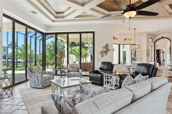 Living room featuring beamed ceiling, ceiling fan, coffered ceiling, and a healthy amount of sunlight