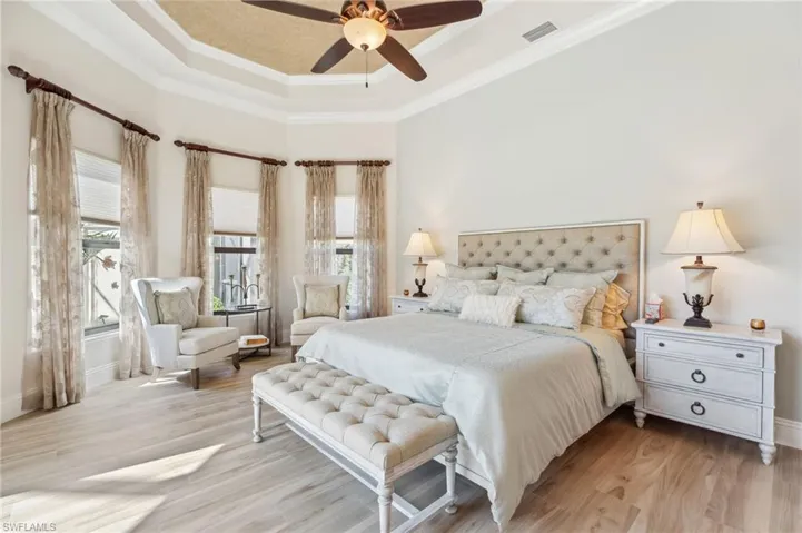 Bedroom with ceiling fan, light wood-type flooring, crown molding, and multiple windows