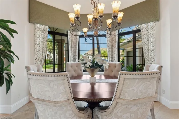 Tiled dining room featuring a chandelier and a healthy amount of sunlight