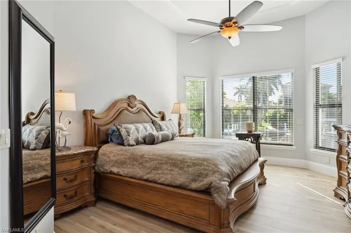 Bedroom with light wood-type flooring, ceiling fan, and high vaulted ceiling
