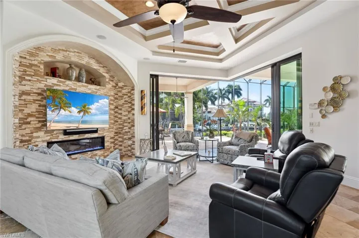 Living room featuring ceiling fan, crown molding, beam ceiling, and coffered ceiling