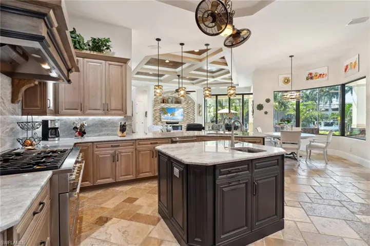 Kitchen featuring sink, tasteful backsplash, a center island with sink, coffered ceiling, and high end stove