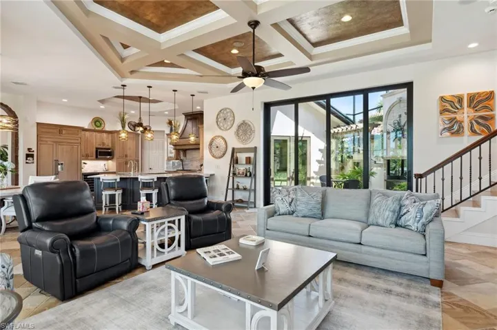 Living room with coffered ceiling, crown molding, beam ceiling, ceiling fan, and sink