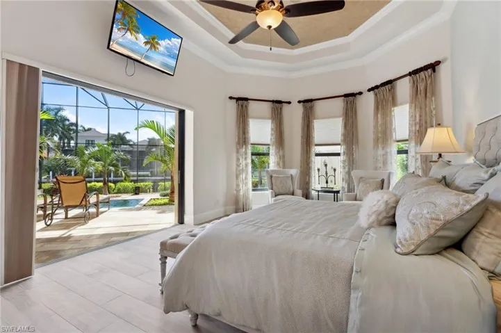 Bedroom featuring a raised ceiling, ornamental molding, a towering ceiling, and ceiling fan