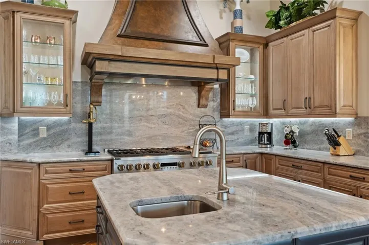 Kitchen featuring light stone counters, sink, and decorative backsplash