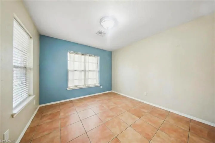 Empty room with light tile patterned flooring and baseboards