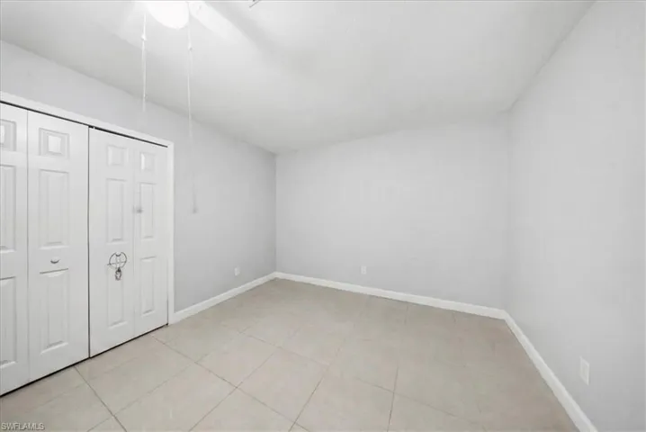 Unfurnished bedroom with a closet, light tile patterned floors, and a ceiling fan
