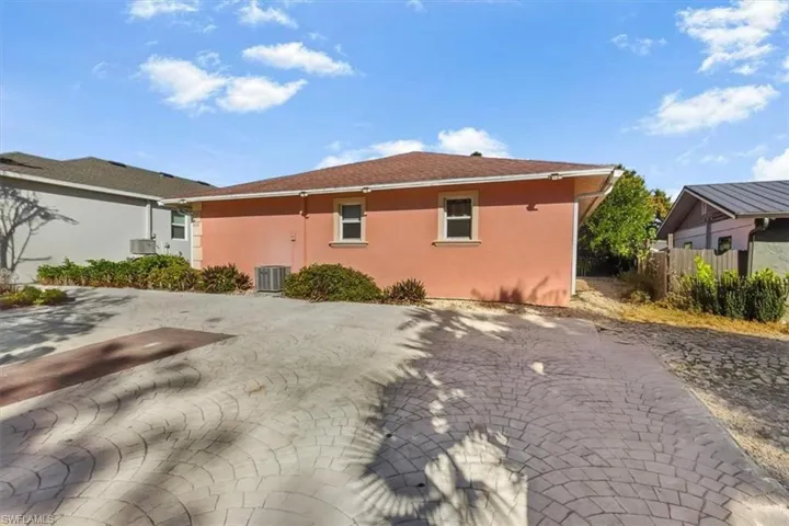 View of side of home featuring stucco siding, decorative driveway, and a patio area