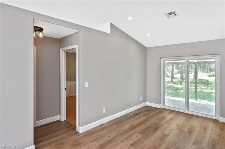 Unfurnished room featuring light wood-type flooring and vaulted ceiling