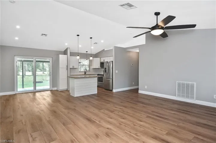 Kitchen featuring white cabinets, lofted ceiling, hanging light fixtures