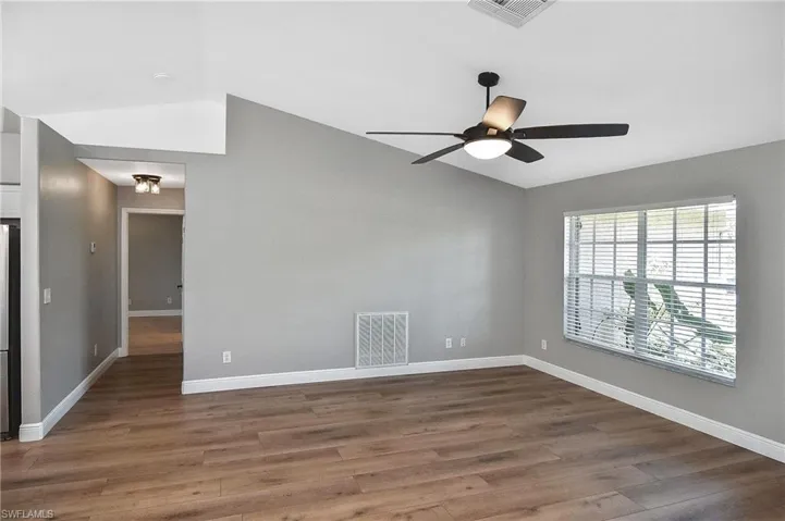 Unfurnished room with ceiling fan, vaulted ceiling, and dark hardwood / wood-style flooring