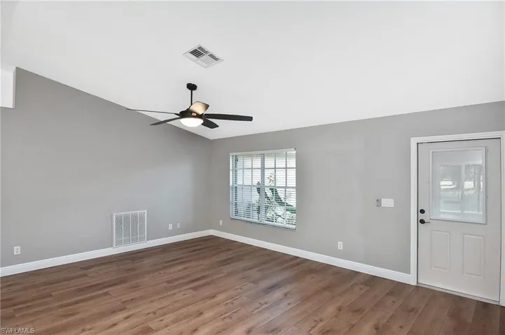 Empty room with lofted ceiling, ceiling fan, and hardwood / wood-style flooring
