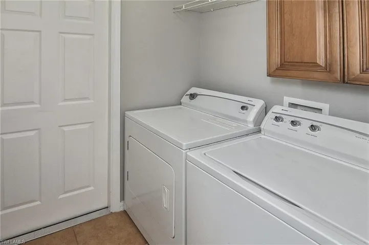 Laundry area featuring washer and clothes dryer, cabinets, and light tile patterned flooring