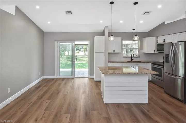 Kitchen featuring stainless steel appliances, plenty of natural light, white cabinetry, and a center island