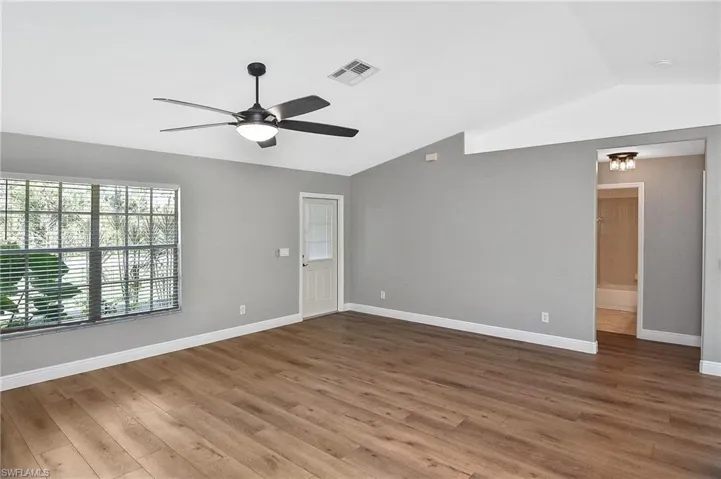 Spare room with vaulted ceiling, ceiling fan, and hardwood / wood-style flooring
