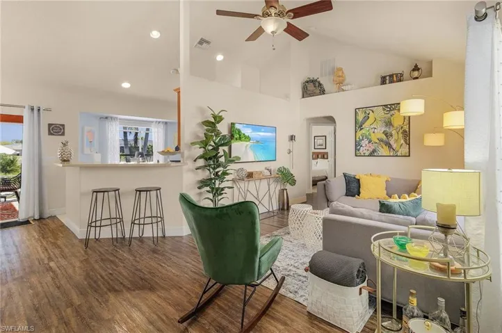 Living room featuring high vaulted ceiling, dark wood-style floors, arched walkways, ceiling fan, and recessed lighting