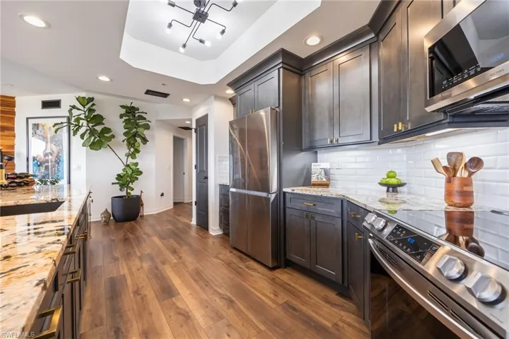 Kitchen with appliances with stainless steel finishes, light stone countertops, dark wood-style floors, recessed lighting, and decorative backsplash