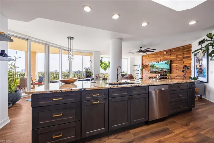 Kitchen with light stone countertops, dishwasher, dark wood-style flooring, wooden walls, and recessed lighting
