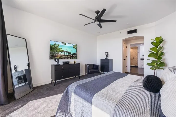 Carpeted bedroom with arched walkways and a ceiling fan