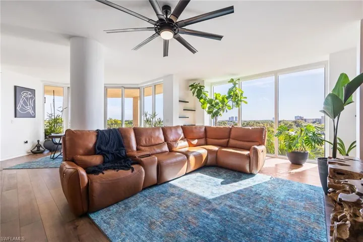 Living area featuring wood-type flooring, floor to ceiling windows, and a ceiling fan