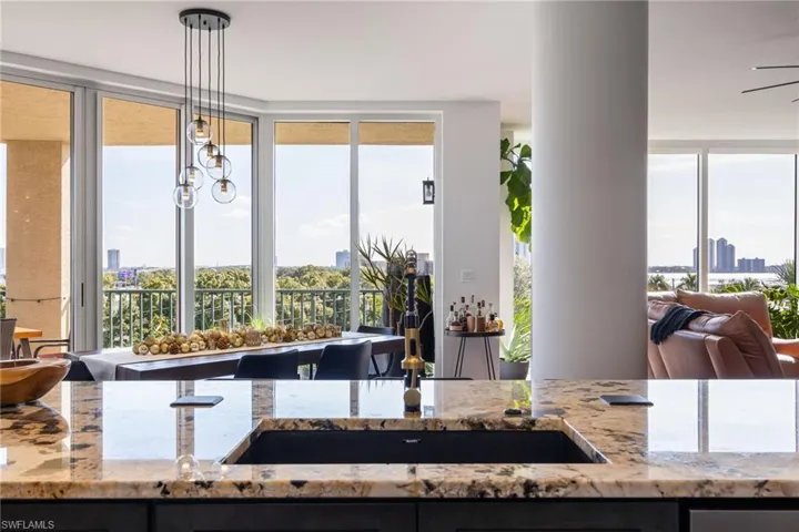 Kitchen featuring light stone countertops, hanging light fixtures, a city view, a chandelier, and healthy amount of natural light