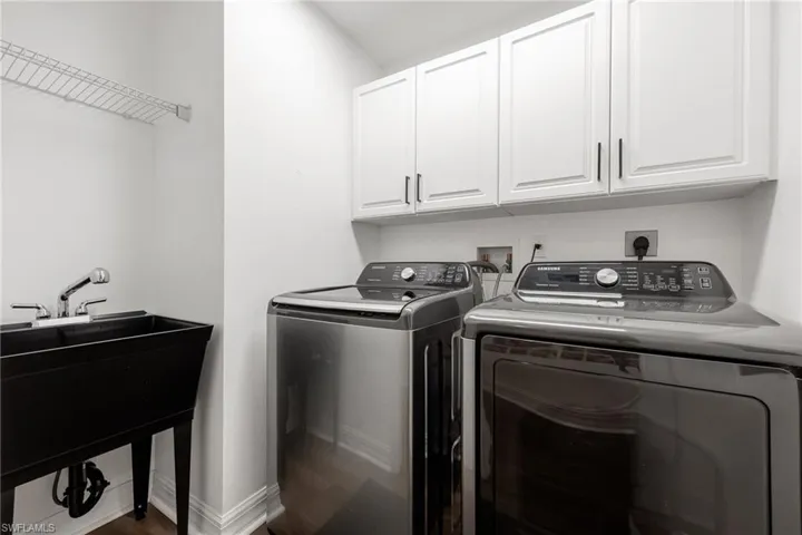 Laundry area featuring washer and dryer, cabinet space, and wood finished floors
