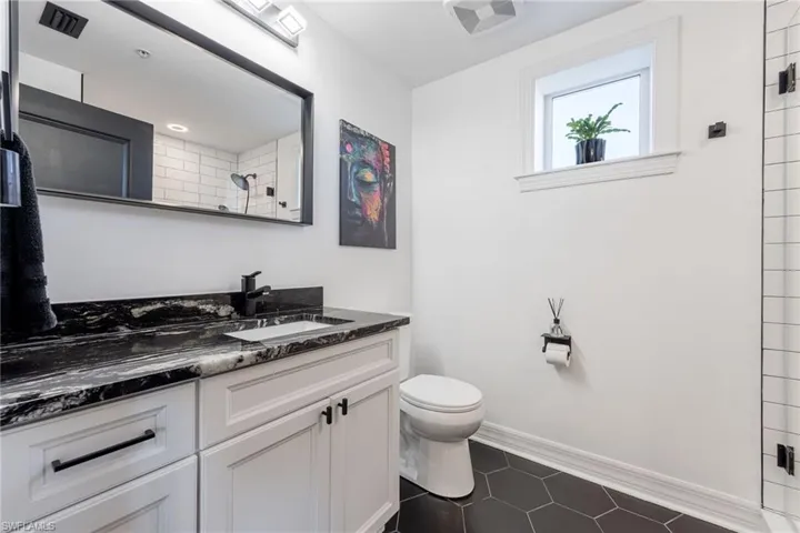 Bathroom featuring vanity, dark tile patterned flooring, and tiled shower
