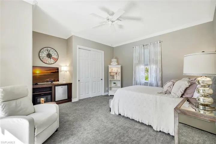 Carpeted bedroom with ornamental molding, a closet, and ceiling fan