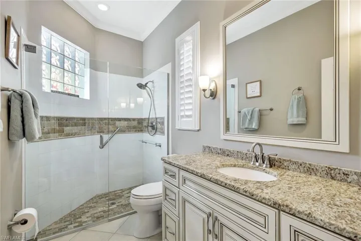 Bathroom with vanity, a stall shower, ornamental molding, and light tile patterned floors