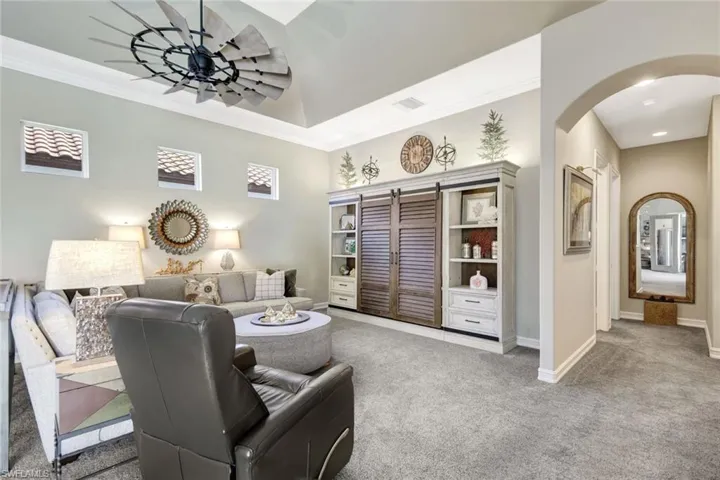 Living room with carpet floors, ornamental molding, and arched walkways