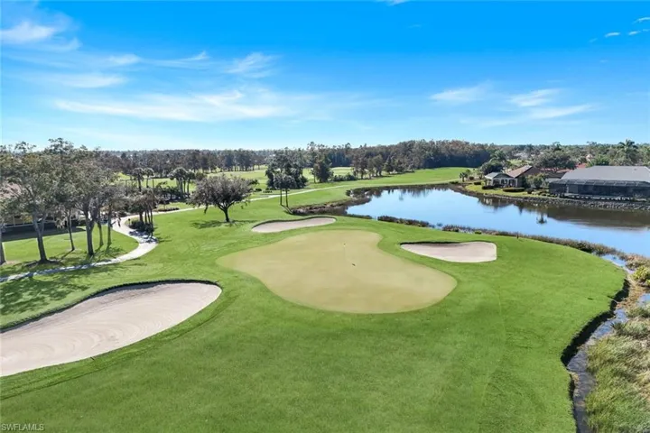 View of community featuring a water view, view of golf course, view of scattered trees, and a yard