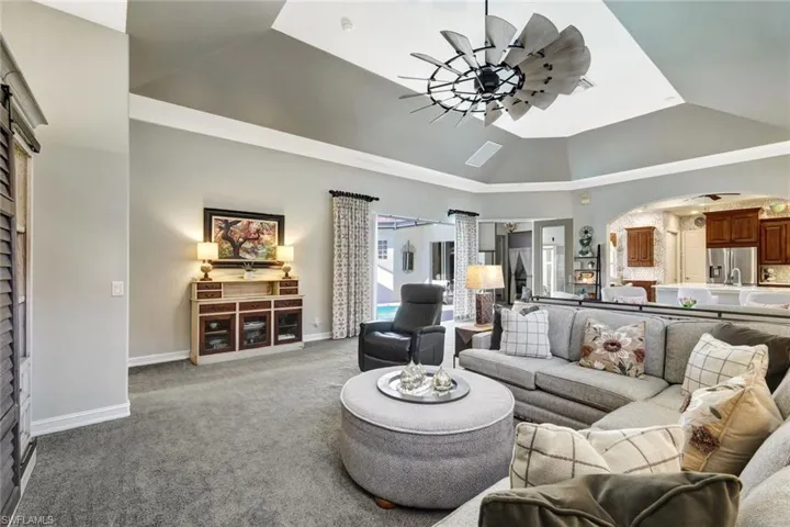 Living area featuring ceiling fan, vaulted ceiling, and carpet floors