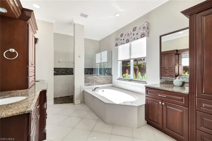 Bathroom with walk in shower, a garden tub, light tile patterned floors, vanity, and ornamental molding