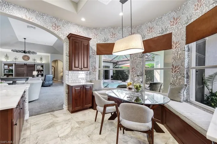 Dining area with arched walkways, light colored carpet, and lofted ceiling