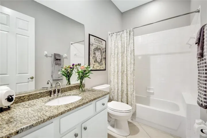 Bathroom with shower / bath combo with shower curtain, vanity, and light tile patterned floors