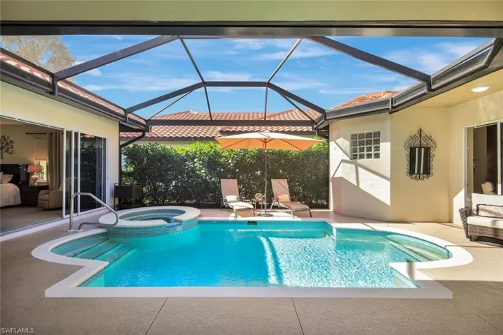 View of swimming pool with a patio area, a sunroom, a pool with connected hot tub, and a lanai