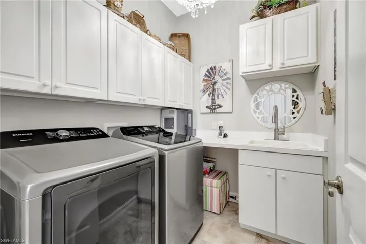 Laundry area featuring cabinet space, independent washer and dryer, and a chandelier