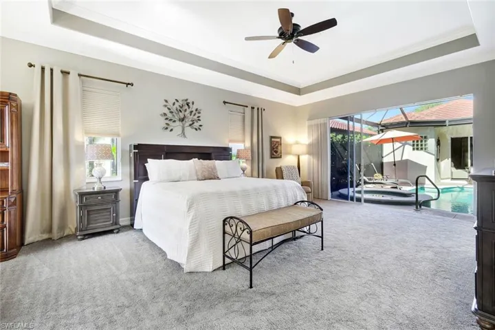 Carpeted bedroom with a raised ceiling, a sunroom, ornamental molding, ceiling fan, and access to exterior