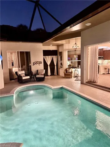Outdoor pool with glass enclosure, a patio, a sunroom, and an outdoor living space