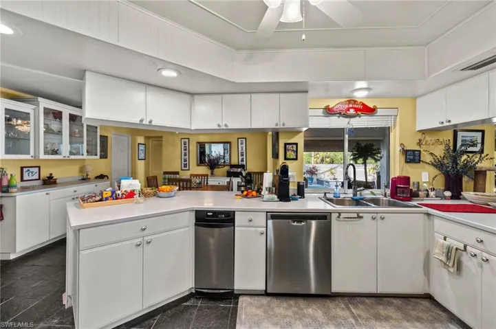 Kitchen featuring a peninsula, granite finish floor, a sink, white cabinets, and light countertops