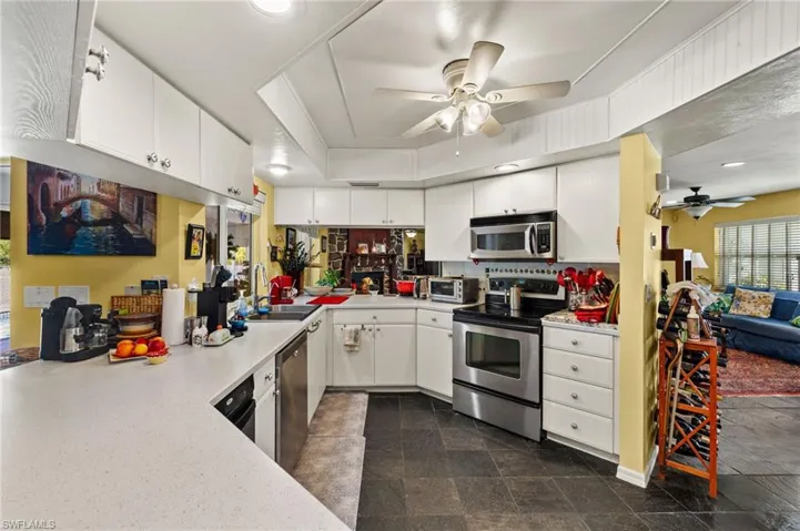 Kitchen with a toaster, stainless steel appliances, light countertops, white cabinetry, and a sink