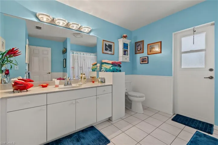 Full bath featuring tile patterned flooring, toilet, a wainscoted wall, visible vents, and vanity